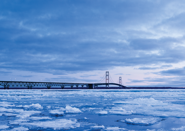 A bridge during sunrise over an ice covered lake.